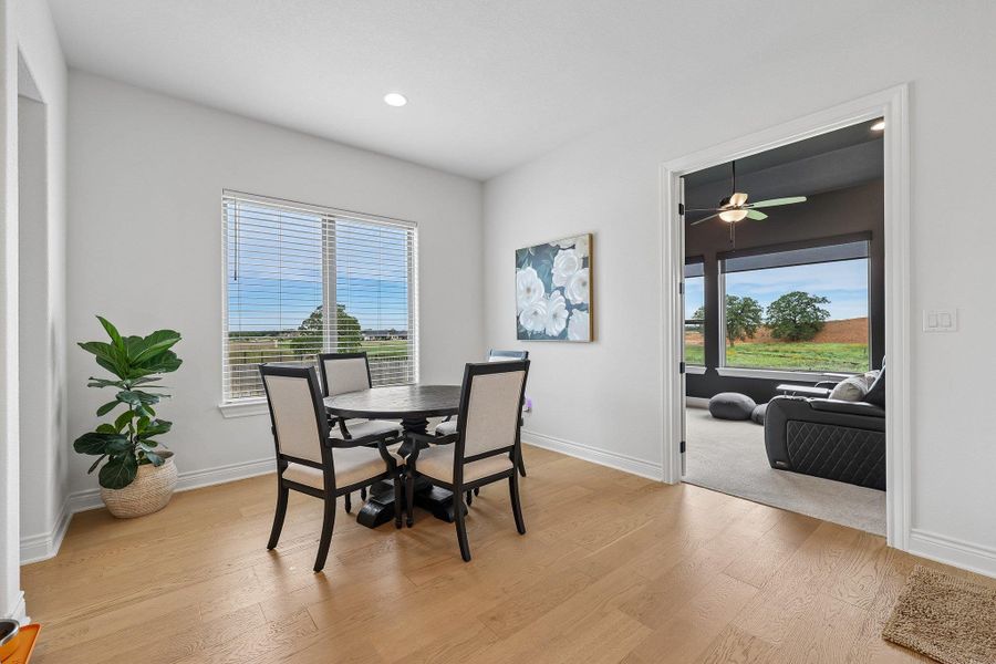 Light wood-finish flooring provides a bright base for this room, featuring white baseboards, light grey walls, and a recessed ceiling light