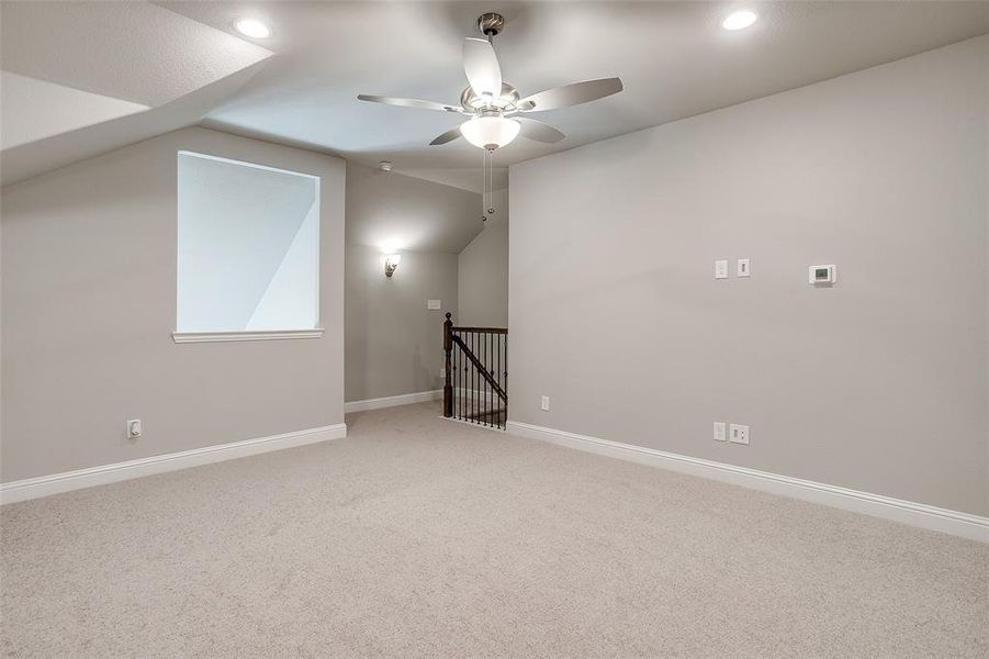 Additional living space with vaulted ceiling, ceiling fan, and carpet flooring Additional living space with vaulted ceiling, ceiling fan, and carpet flooring