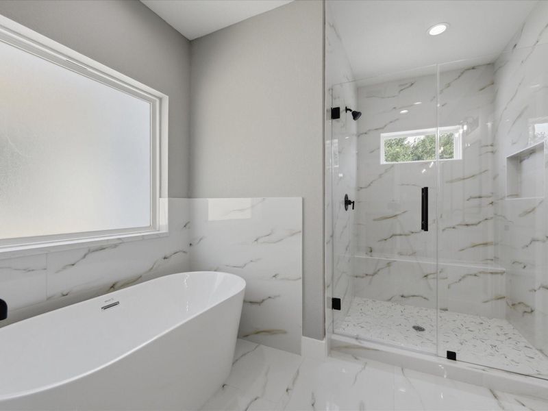 Contemporary finishes, a freestanding soaking tub, and an oversized walk-in shower combine to create a spa-like primary bath experience. Contemporary finishes, a freestanding soaking tub, and an oversized walk-in shower combine to create a spa-like primary bath experience.