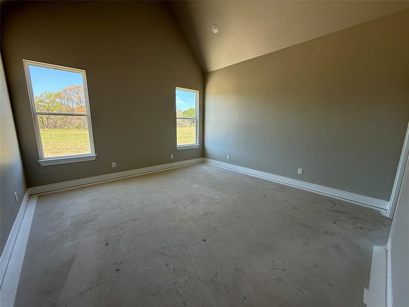 Empty room featuring unfinished concrete floors and lofted ceiling