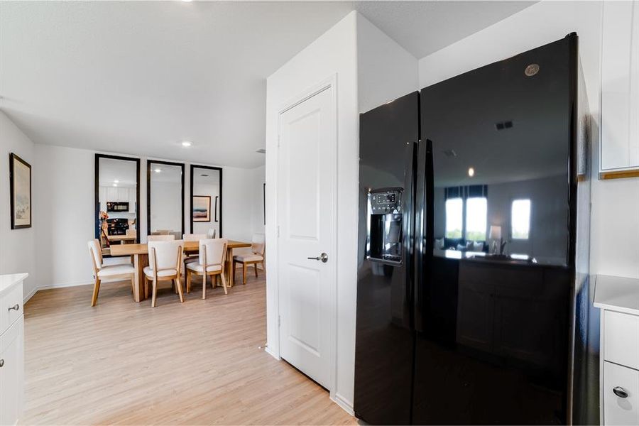 Kitchen with black fridge with ice dispenser, white cabinets, light wood-type flooring, recessed lighting, and light countertops Kitchen with black fridge with ice dispenser, white cabinets, light wood-type flooring, recessed lighting, and light countertops