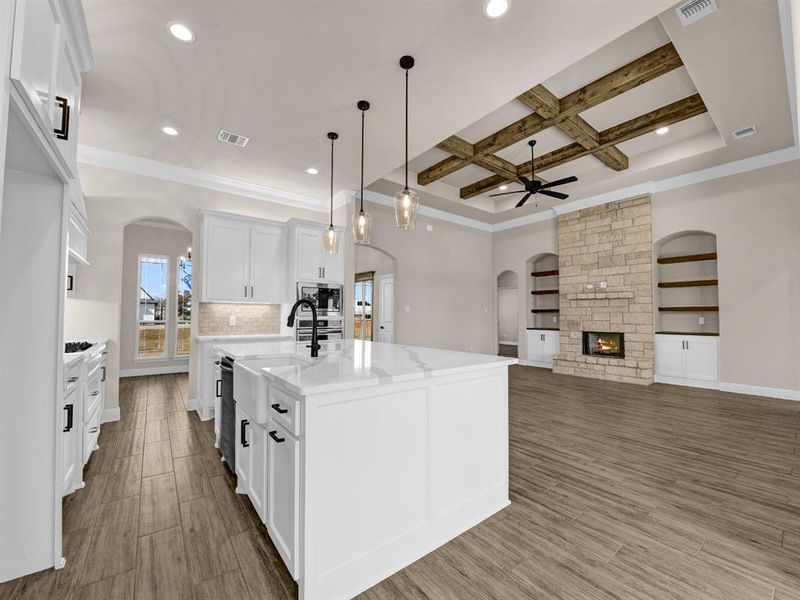 Kitchen featuring coffered ceiling, a kitchen island with sink, appliances with stainless steel finishes, ceiling fan, and white cabinets