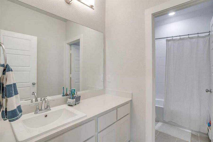 Full bath featuring shower / tub combo with curtain, vanity, and light tile patterned flooring Full bath featuring shower / tub combo with curtain, vanity, and light tile patterned flooring