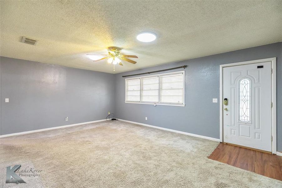 Carpeted foyer entrance featuring a textured ceiling and a ceiling fan