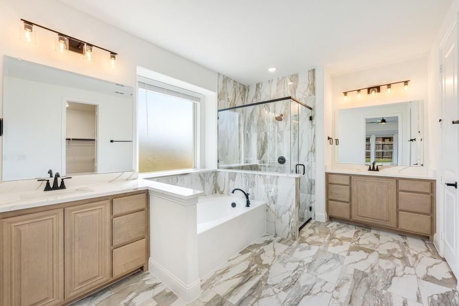 Master bathroom with marble tile floors, soaking tub, glass shower, and dual wood vanities with mirrors Master bathroom with marble tile floors, soaking tub, glass shower, and dual wood vanities with mirrors