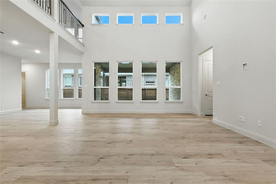 Unfurnished living room featuring light wood finished floors and a high ceiling