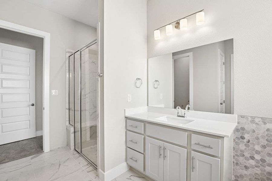 Bathroom with a marble finish shower, vanity, and light marble finish flooring Bathroom with a marble finish shower, vanity, and light marble finish flooring