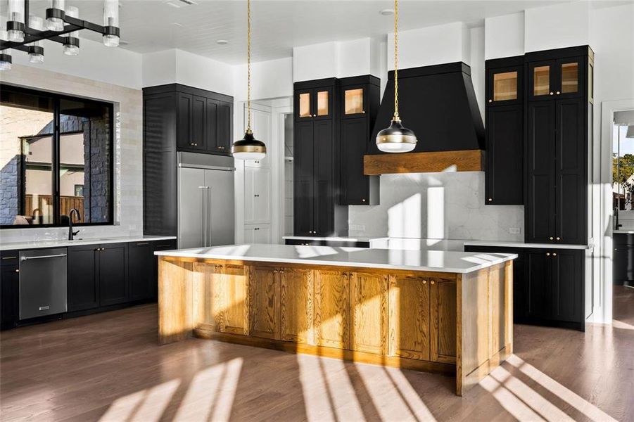 Kitchen with dark cabinets, glass insert cabinets, decorative light fixtures, and dark wood finished floors Kitchen with dark cabinets, glass insert cabinets, decorative light fixtures, and dark wood finished floors