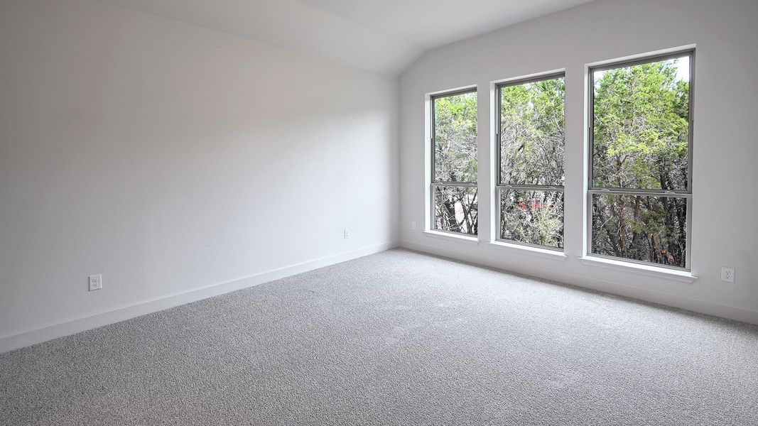 Carpeted empty room featuring baseboards and vaulted ceiling