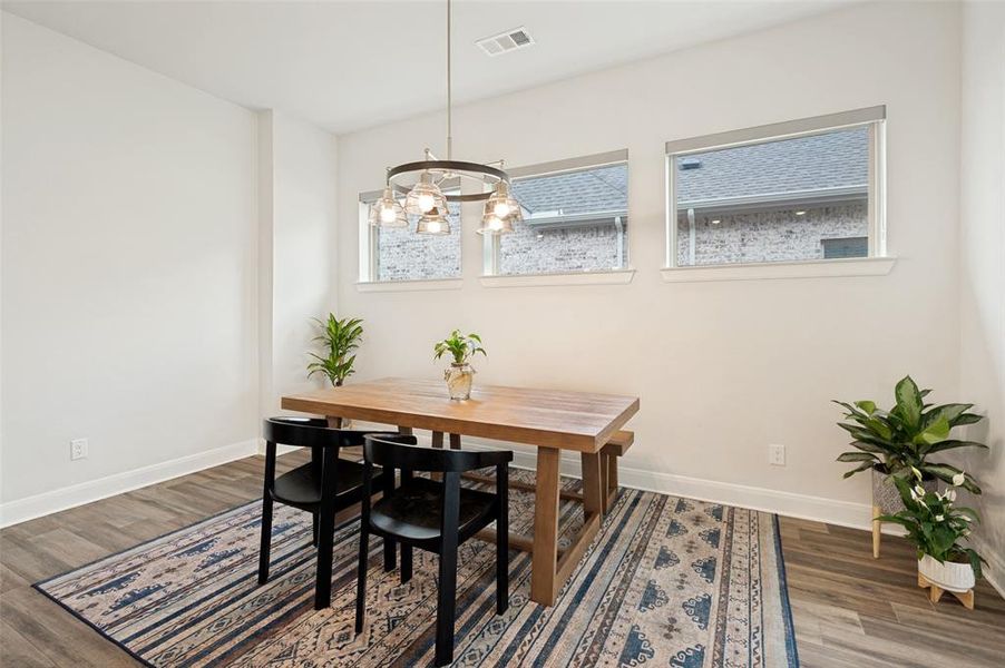 Dining space featuring wood-finish flooring, white baseboards, and a contemporary chandelier