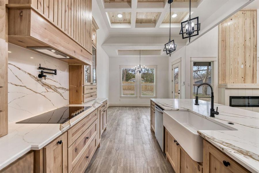 Kitchen with light stone countertops, coffered ceiling, wood finished floors, black electric stovetop, and tasteful backsplash