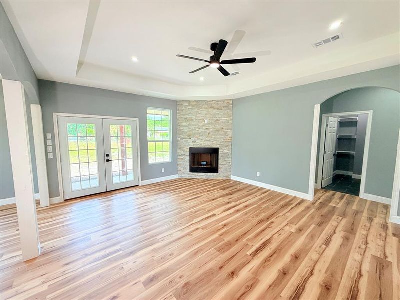 Spacious room with wood-finish flooring, a tray ceiling, and recessed lighting