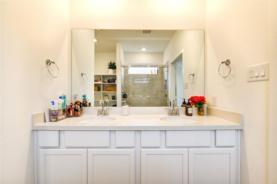 The primary bath features double vanities with expansive wall-to-wall mirrors and generous drawer and cabinet storage, creating a well-organized and highly functional space. Thoughtfully designed for both convenience and comfort, it offers an ideal setting for daily routines while maintaining a polished and refined look.