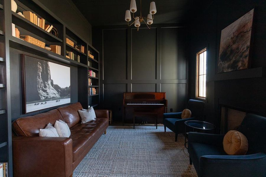 Living area featuring built in features, a decorative wall, a fireplace, a chandelier, and a high ceiling