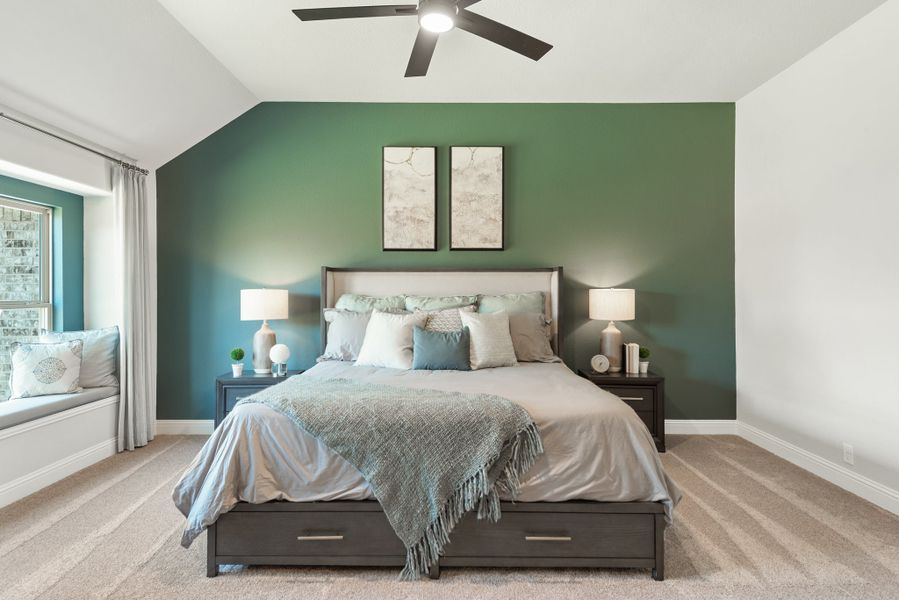 Bedroom with green accent wall, vaulted ceiling, ceiling fan, and window seat