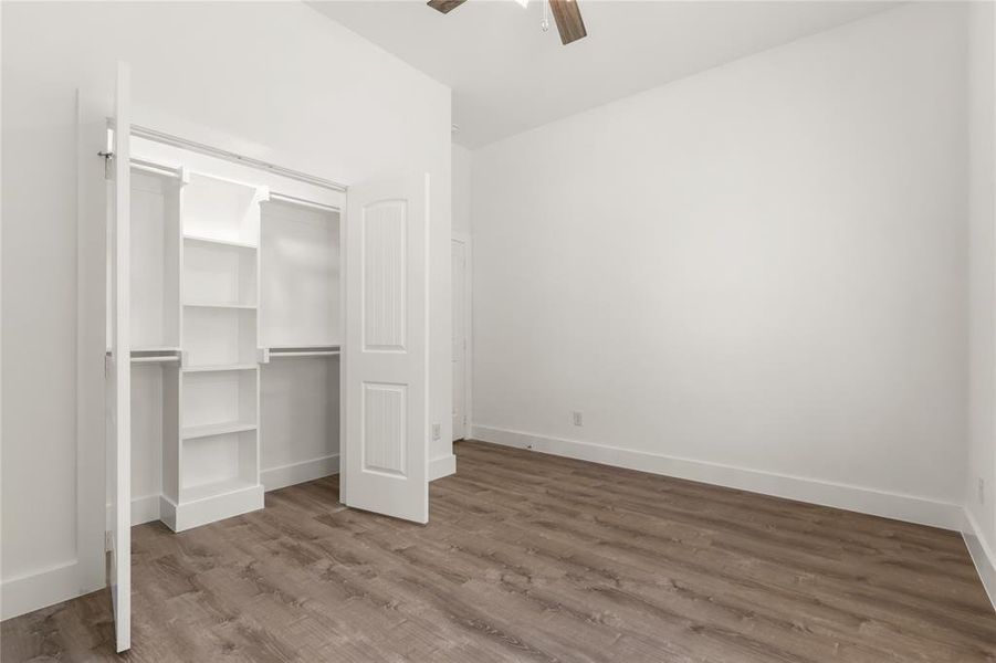 Unfurnished bedroom featuring hardwood / wood-style floors, a closet, and ceiling fan