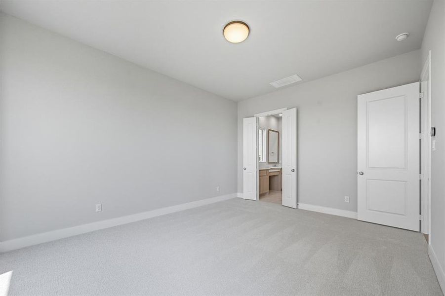 Unfurnished bedroom featuring light colored carpet and connected bathroom