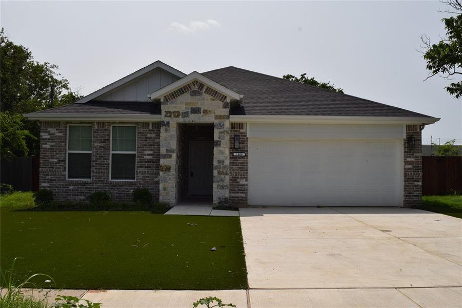 View of front of home featuring an attached garage, brick siding, concrete driveway, and board and batten siding