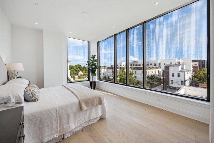 Primary bedroom with south facing windows.  Beautiful wide plank wood floors, tall ceilings, and recessed lighting.