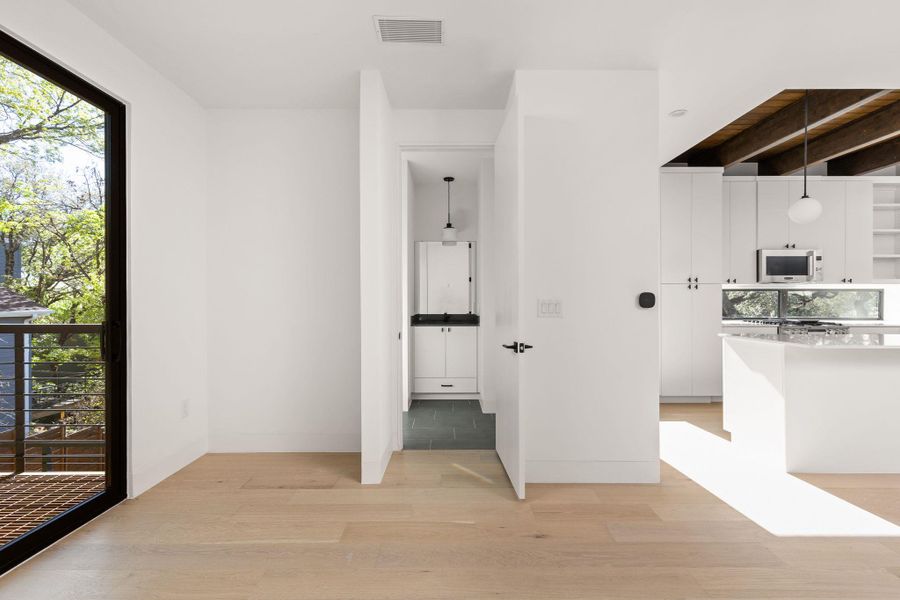 Kitchen with light wood-style floors, hanging light fixtures, light stone counters, white cabinetry, and open shelves
