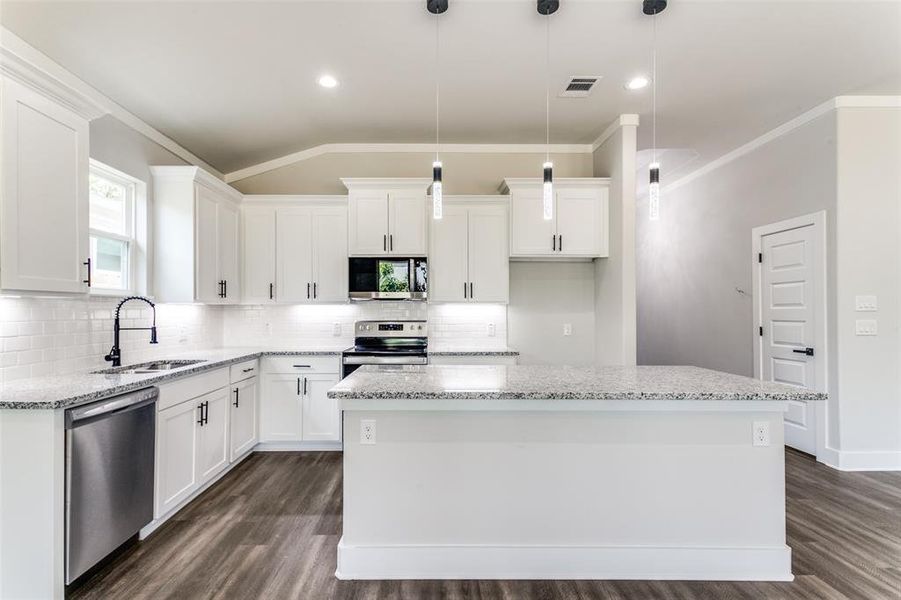 Kitchen with dark wood-type flooring, a kitchen island, appliances with stainless steel finishes, and sink