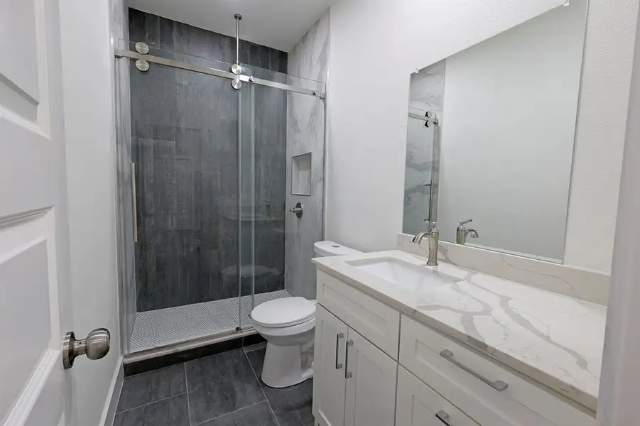 Bathroom featuring a shower stall, vanity, and dark tile patterned floors Bathroom featuring a shower stall, vanity, and dark tile patterned floors
