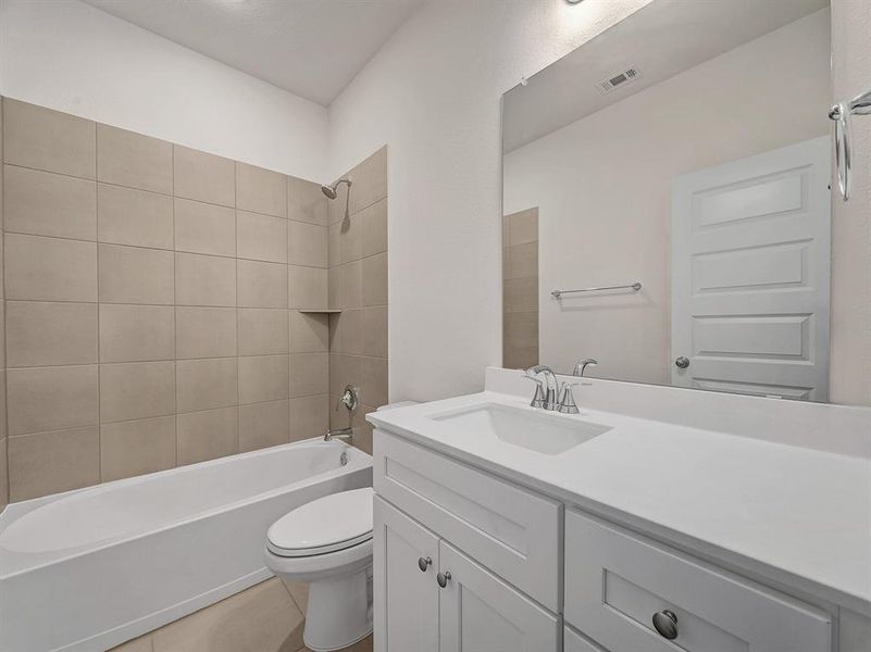 Full bathroom with tile patterned flooring, vanity, toilet, and tiled shower / bath