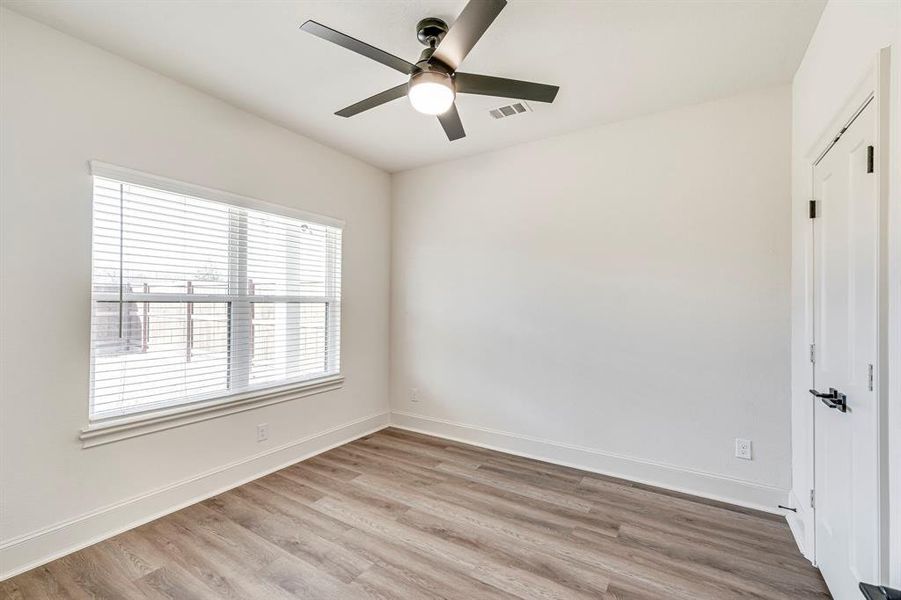 Spare room with a ceiling fan, baseboards, light wood-style floors, and visible vents Spare room with a ceiling fan, baseboards, light wood-style floors, and visible vents