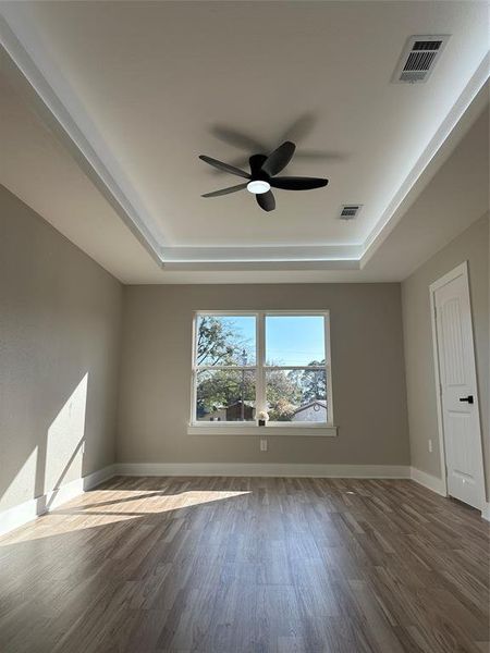 Unfurnished room featuring dark hardwood / wood-style floors, ceiling fan, and a raised ceiling