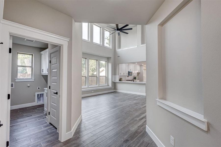Entrance with full utility room featuring dark wood look tiled floors, a ceiling fan, and a high ceiling