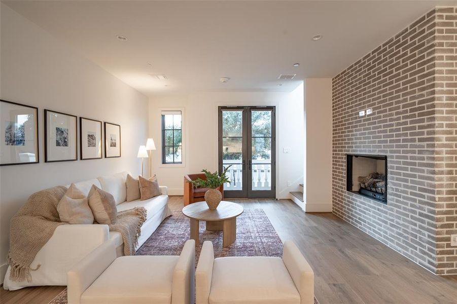 Living room featuring a fireplace, light wood-type flooring, and french doors