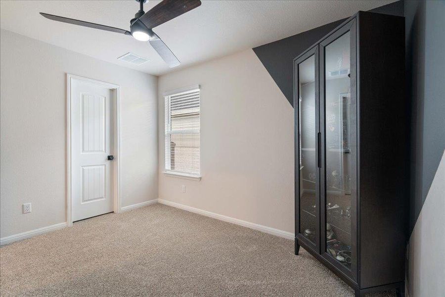Unfurnished bedroom with baseboards, carpet flooring, visible vents, and a ceiling fan