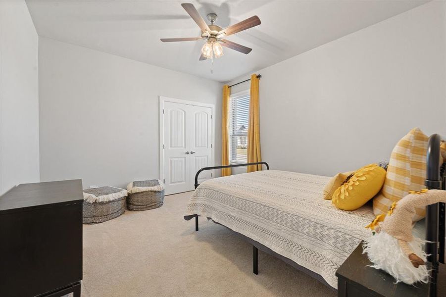 Bedroom with light carpet and a ceiling fan