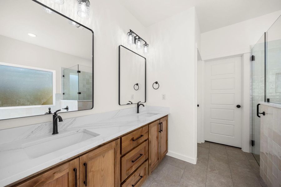 Dual vanities with elegant stone counters provide ample space in this well-appointed bath.