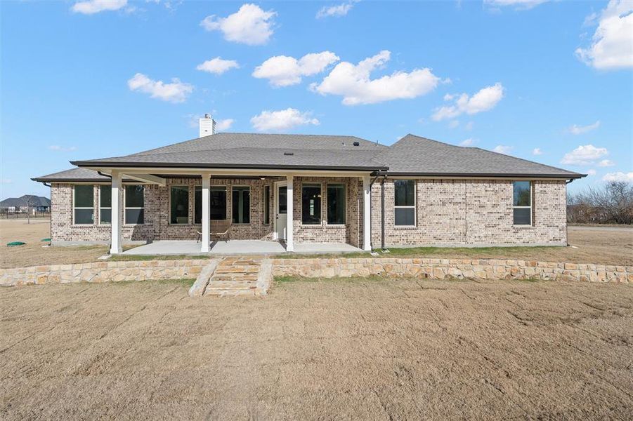 Back of house with a patio area, brick siding, a chimney, and a shingled roof