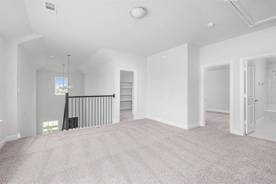 Carpeted empty room with visible vents, vaulted ceiling, and baseboards