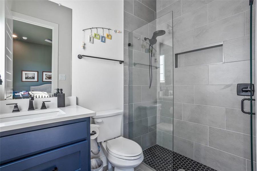 Upgraded secondary bath, frameless glass shower and specialty tile with a pop of color on the cabinetry