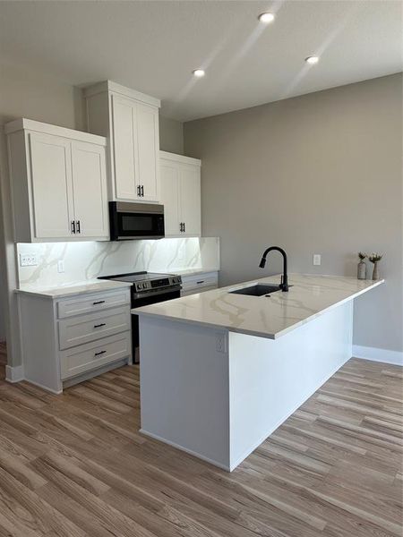 Kitchen featuring decorative backsplash, sink, white cabinets, and range