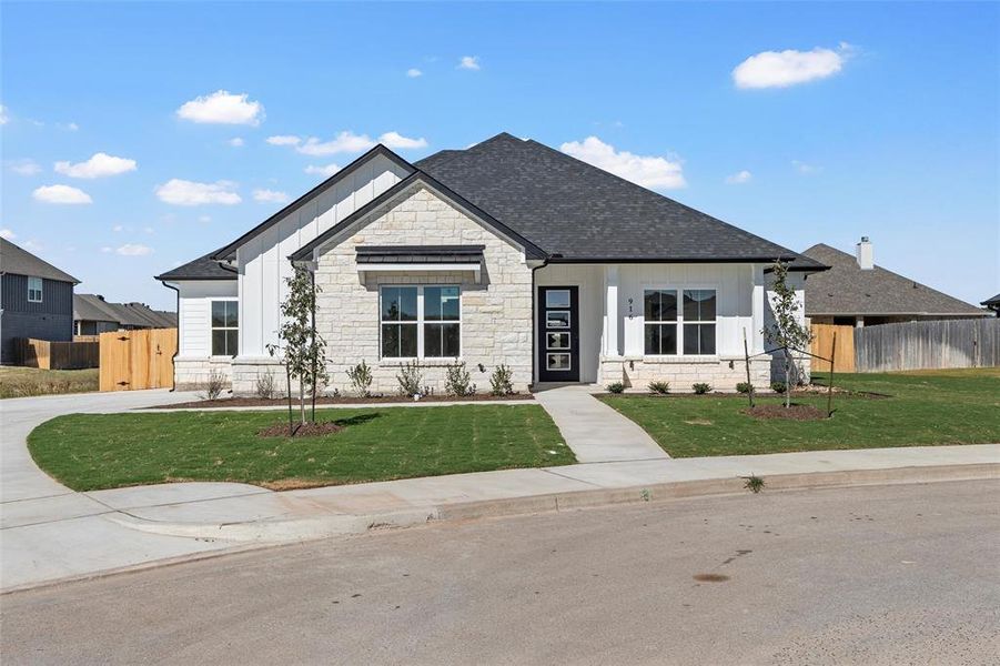 View of front of property featuring stone siding, board and batten siding, and roof with shingles