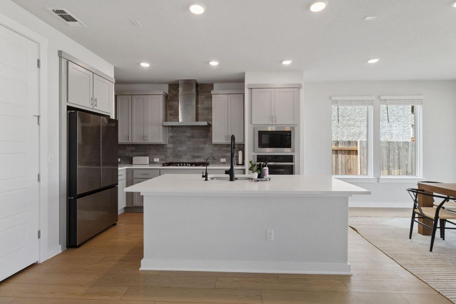 Kitchen featuring stainless steel microwave, oven, and large island with breakfast bar