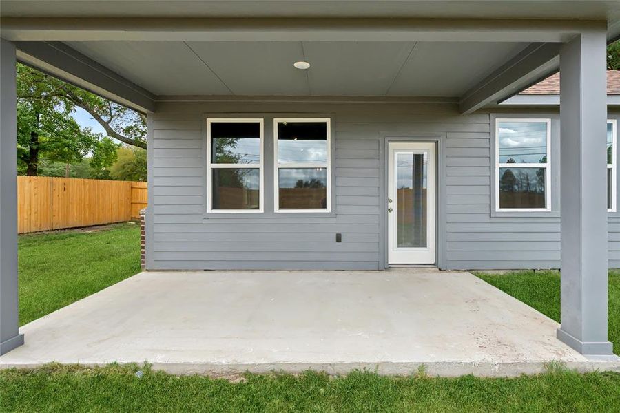 Entrance to property with a patio area and a lawn