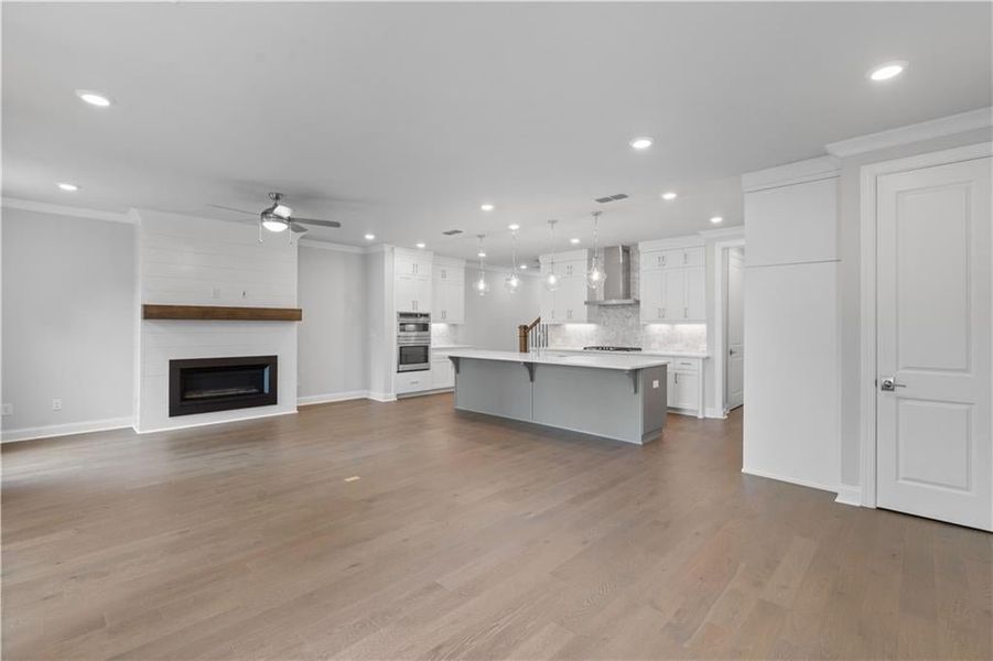 Unfurnished living room with ornamental molding, recessed lighting, dark wood-style floors, a fireplace, and ceiling fan Unfurnished living room with ornamental molding, recessed lighting, dark wood-style floors, a fireplace, and ceiling fan