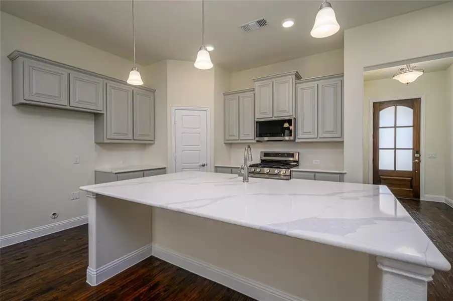Kitchen with quartz countertops with  decorative light fixtures, appliances with stainless steel finishes, and gray cabinetry