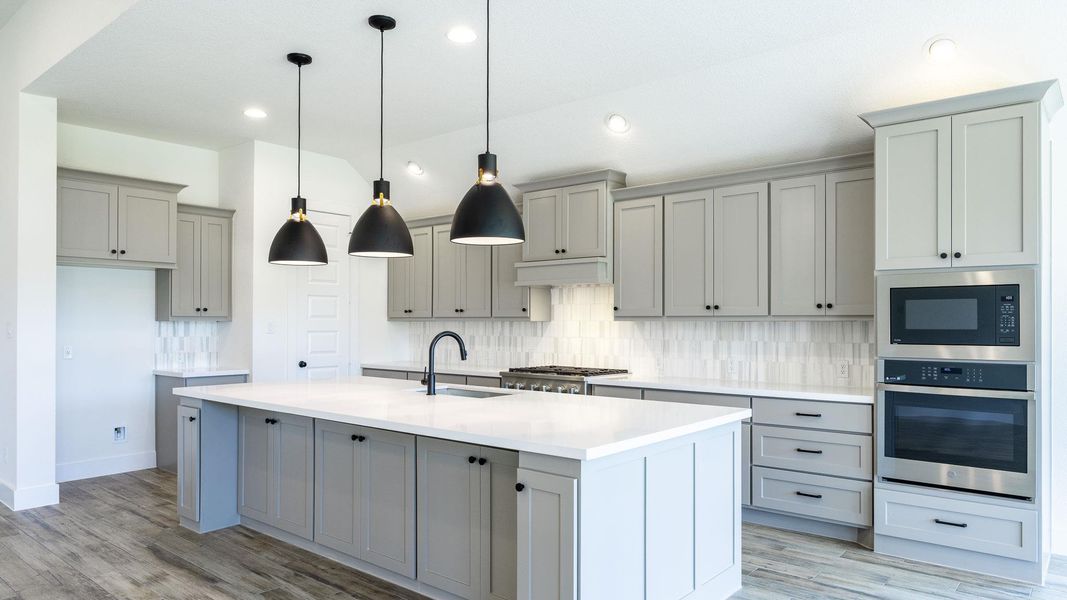 Kitchen with a sink, gray cabinets, decorative backsplash, and appliances with stainless steel finishes Kitchen with a sink, gray cabinets, decorative backsplash, and appliances with stainless steel finishes