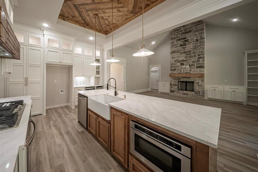 Kitchen featuring vaulted ceiling, glass insert cabinets, recessed lighting, light stone countertops, and white cabinetry Kitchen featuring vaulted ceiling, glass insert cabinets, recessed lighting, light stone countertops, and white cabinetry