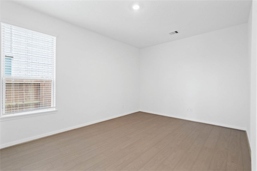 Tucked peacefully at the front of the home, this Den offers a quiet workspace with vinyl plank flooring, high ceilings, recessed lighting, large window with blinds, and custom paint for a polished finish.