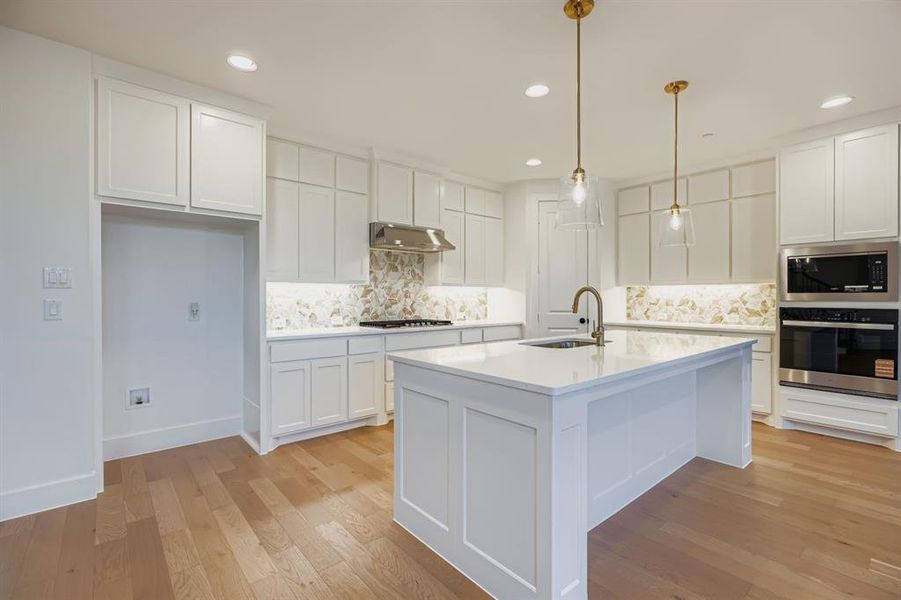 Kitchen with stainless steel appliances, white cabinets, light wood-style floors, and recessed lighting Kitchen with stainless steel appliances, white cabinets, light wood-style floors, and recessed lighting