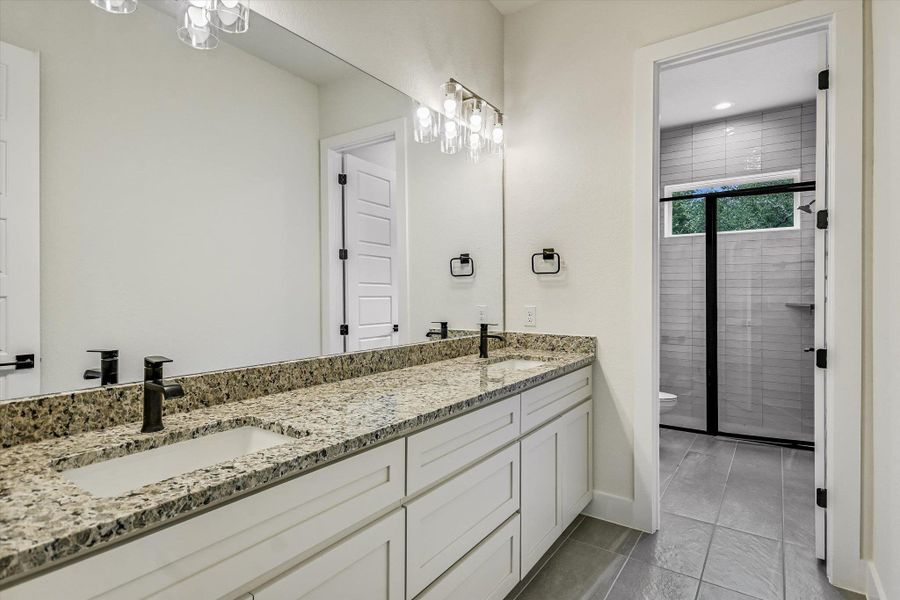 Bathroom with a stall shower, double vanity, and light tile patterned flooring