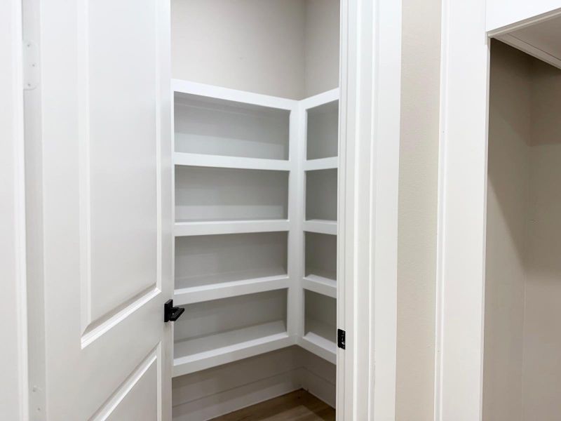 Spacious walk-in pantry with ample shelving for organized storage.