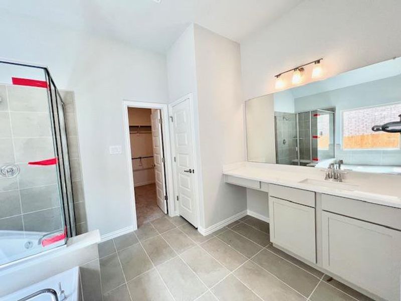 Bathroom featuring tile patterned floors, a tile shower, vanity, and a spacious closet Bathroom featuring tile patterned floors, a tile shower, vanity, and a spacious closet